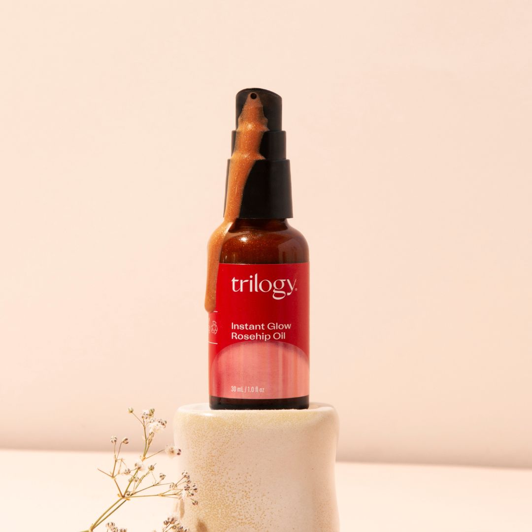 Instant Glow Rosehip Oil with product coming out and a stand.