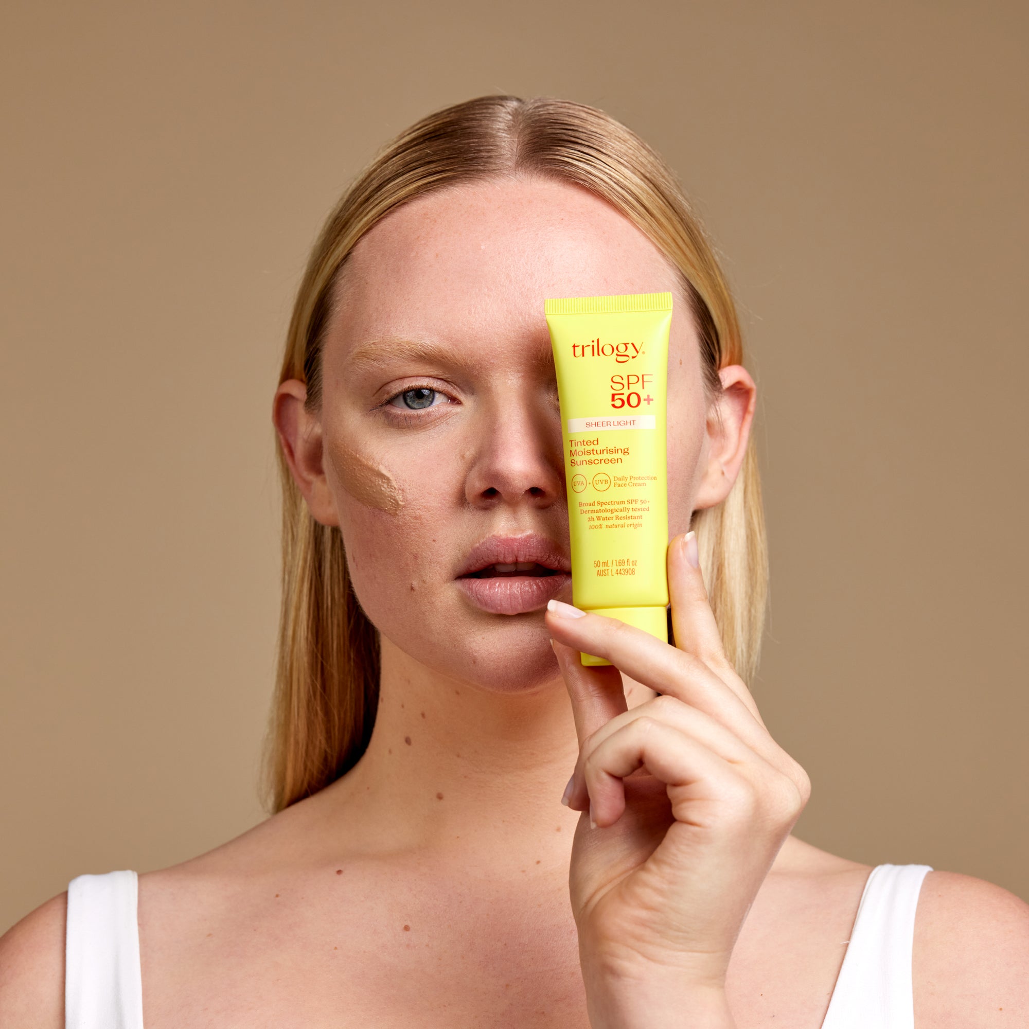 SPF 50+ Sheer Tinted Moisturising Sunscreen light with model and product.