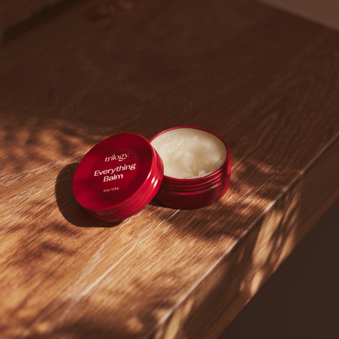 Everything Balm on a table with the lid off showing the texture.